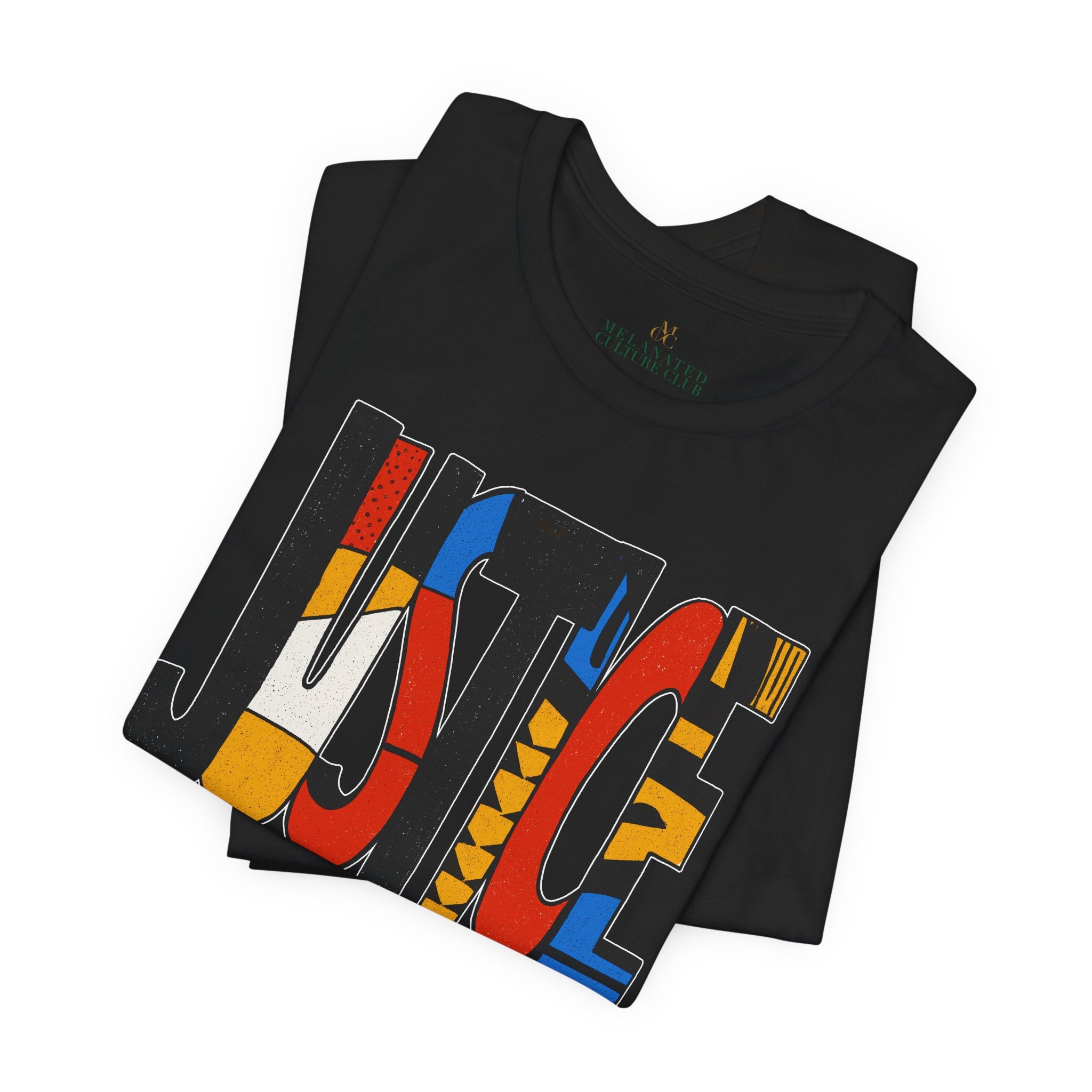 A folded black t-shirt featuring a large graphic print of the word 'JUSTICE' in stylized block letters filled with red, yellow, blue, and white patterns. 