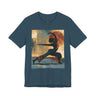 A deep teal colored short-sleeve crewneck t-shirt featuring a Black woman in a yoga pose against a warm, abstract sunset background.