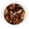 White round wall clock with white time markings and white clock hands, featuring an abstract African-inspired mask face with geometric shapes, circular patterns, and textured details in terracotta, burnt orange, bronze, black, and warm gold tones, displayed against a white background.