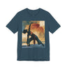 A deep teal colored short-sleeve crewneck t-shirt featuring a Black woman in a yoga pose against a warm, abstract sunset background.