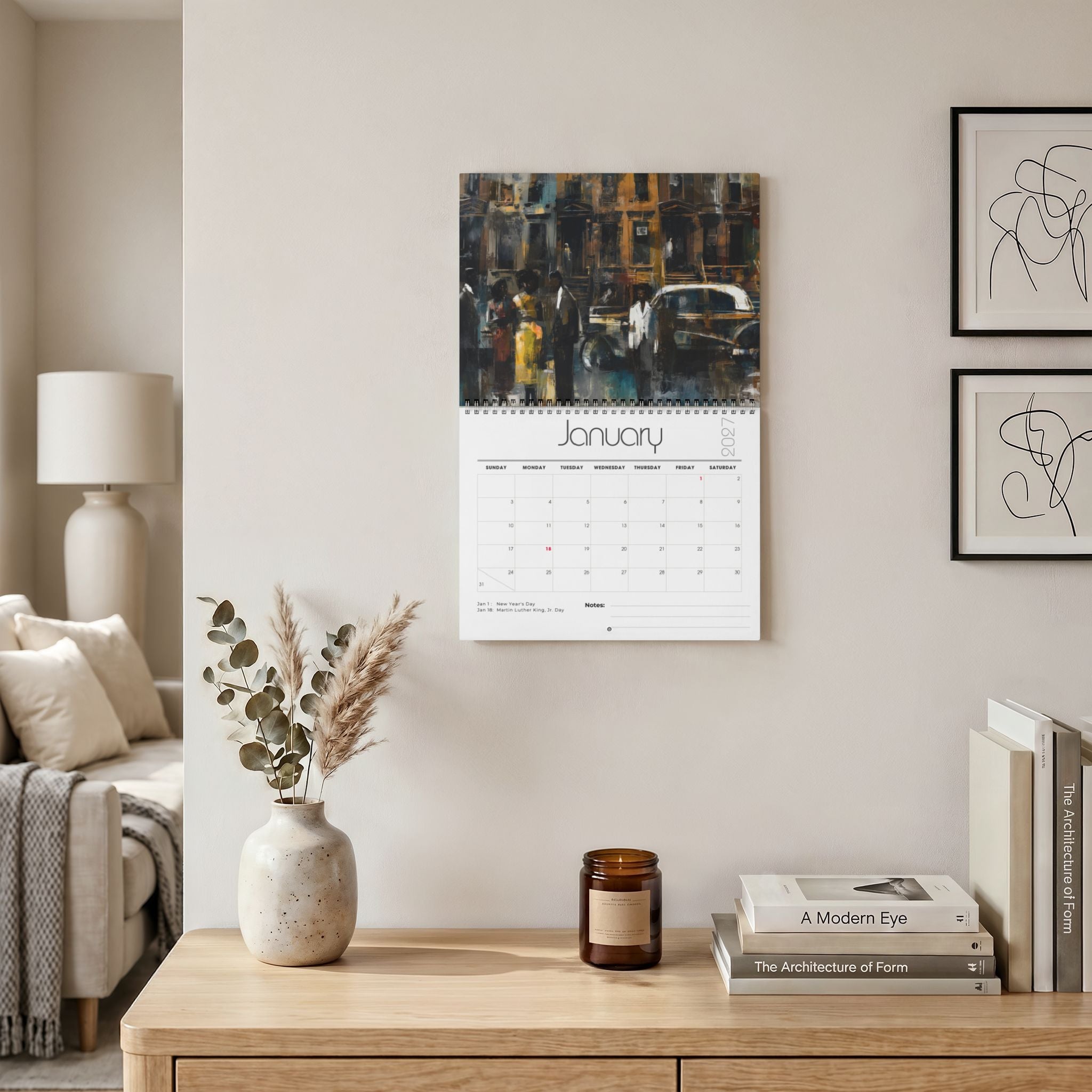 A wall-mounted calendar hanging in a styled living room, with a painting of vintage Harlem street scene across the top and a white January 2027 page below. The room includes a wooden console table, books, a candle, a vase with dried grasses, and framed wall art.  Size 11" x 8.5"