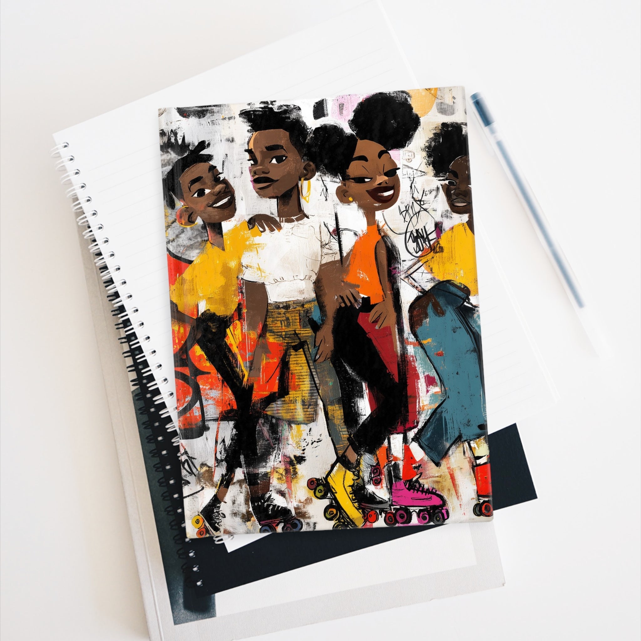 Hardcover journal featuring cartoon style Black teens roller skaters, journal lays on top of various notebooks against a white background.