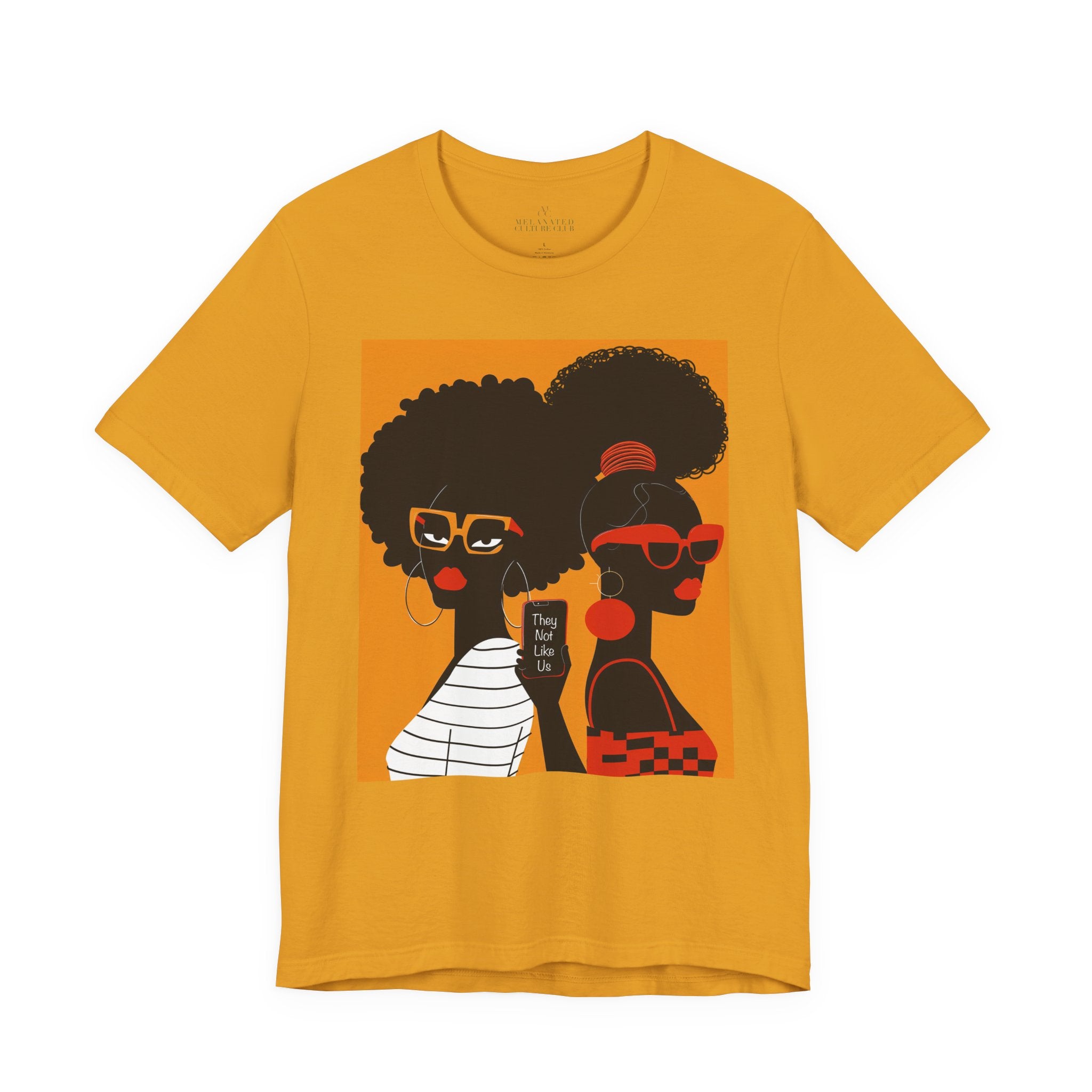They Not Like Us Tee Shirt featuring two Black women in silhouette wearing high-fashion eyewear, holding a cell phone with the phrase "They Not Like Us" on an orange background – Afrocentric unisex apparel.