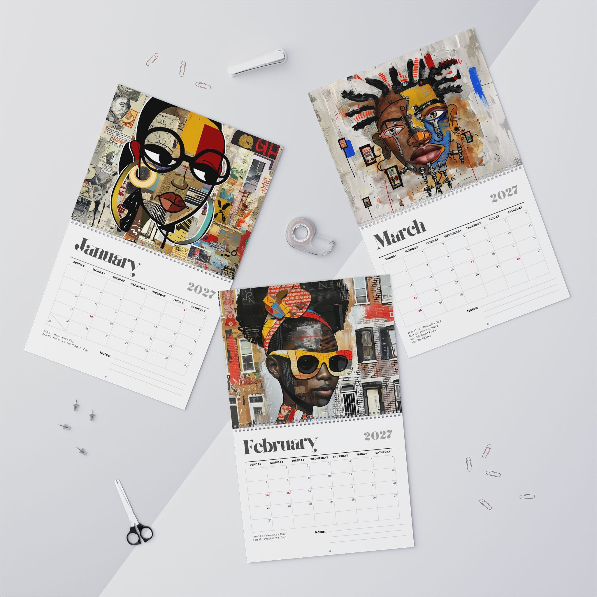 Three spiral-bound Afrocentric Abstract calendars for January, February, and March 2027 are arranged on a light gray surface with art portraits printed on the pages. The calendars feature colorful abstract and portrait illustrations, with the months and years printed on white page layouts.