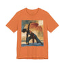 A burnt orange colored short-sleeve crewneck t-shirt featuring a Black woman in a yoga pose against a warm, abstract sunset background.