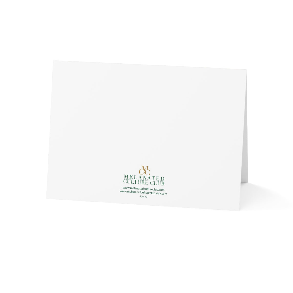 A white folded Christmas greeting card standing upright on a white background, printed with the Melanated Culture Club logo in gold and green near the bottom center.