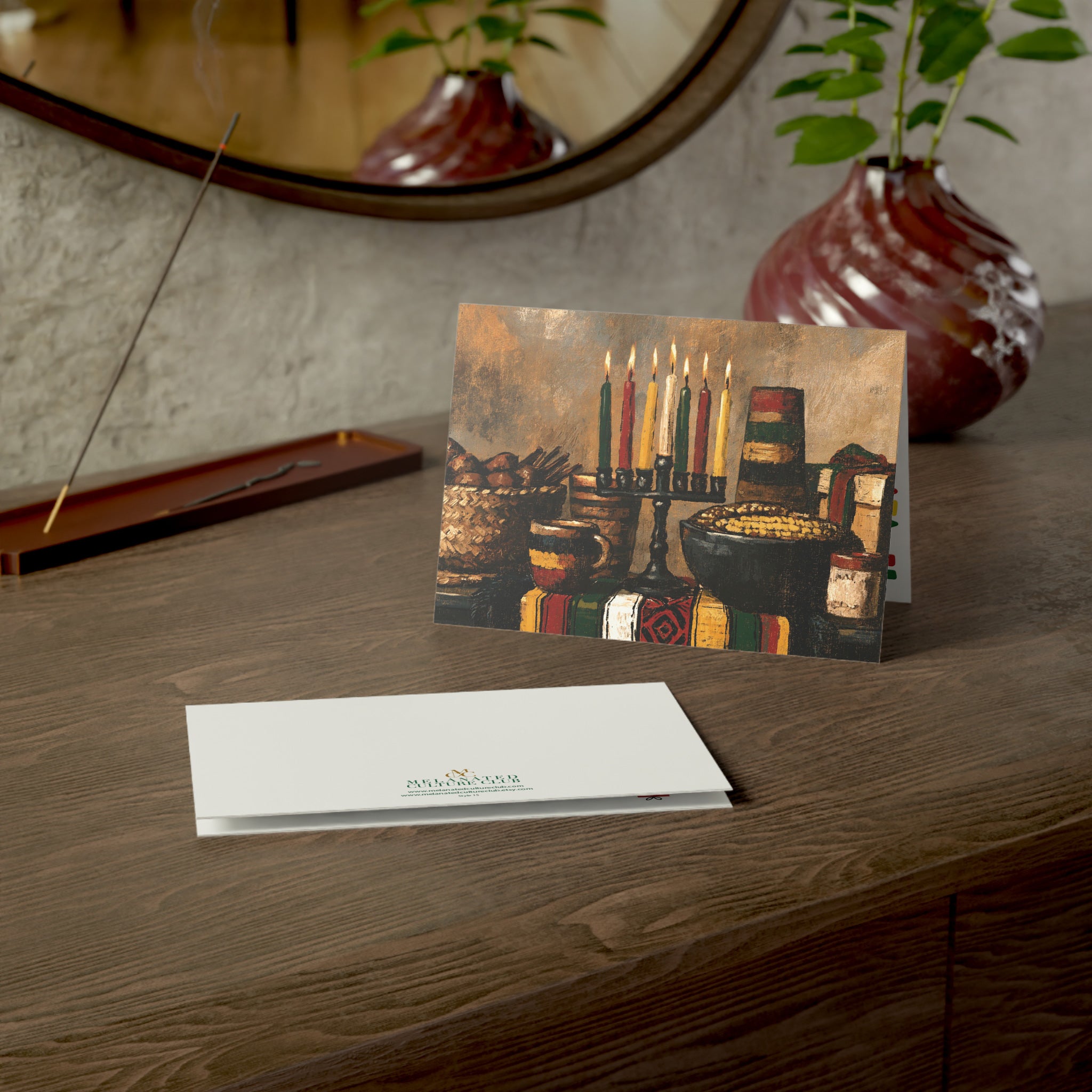 An Afrocentric Kwanzaa holiday greeting card celebrating Black heritage, African American culture, family, unity, community, and the Seven Principles of Kwanzaa, placed on a wood table.