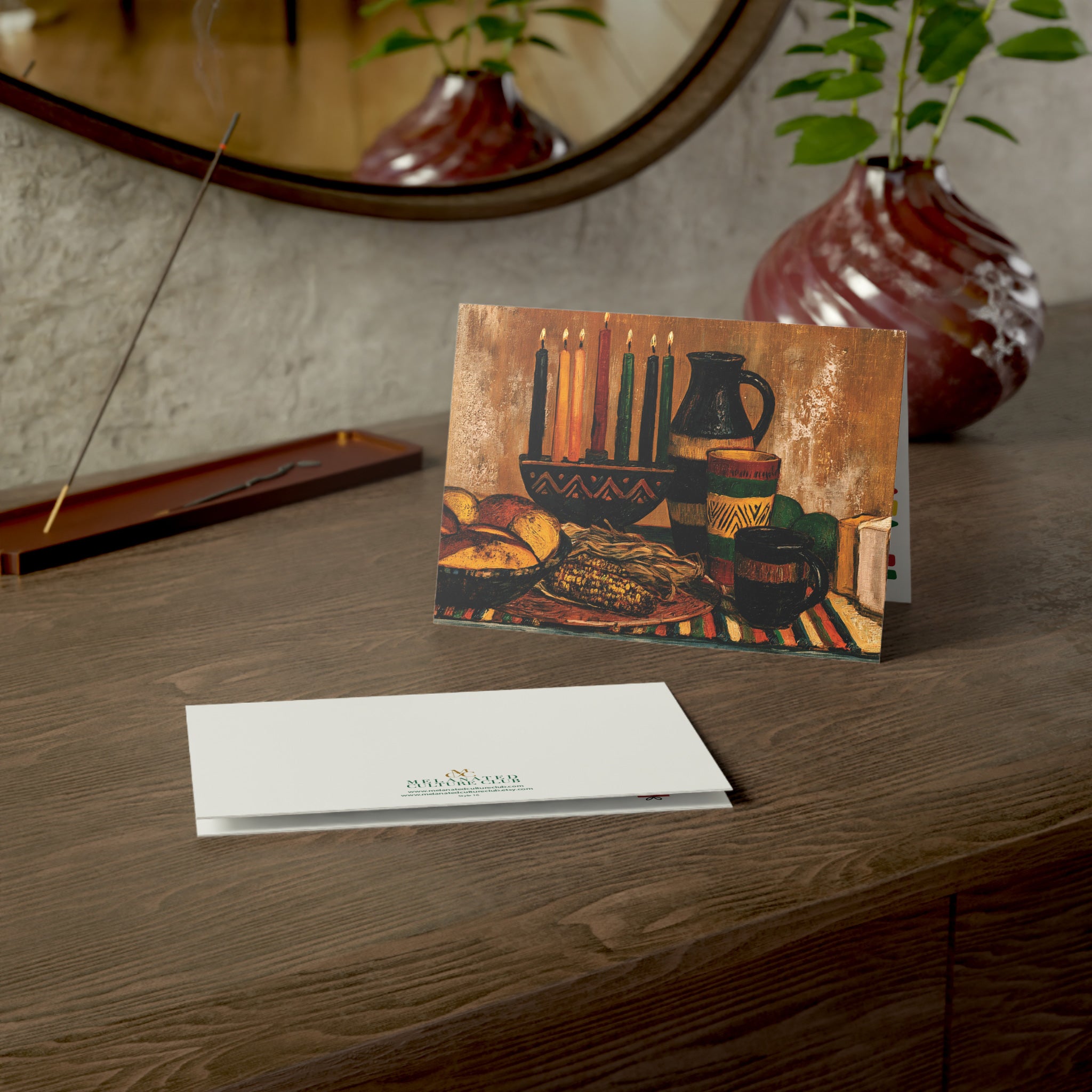 An Afrocentric Kwanzaa holiday greeting card celebrating Black heritage, African American culture, family, unity, community, and the Seven Principles of Kwanzaa, placed on a wood table.