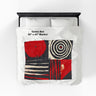 Full view of 50"x60" Afrocentric geometric art throw blanket featuring bold black, red, gold, cream, and neutral abstract patterns with circles, spirals, grids, and textured African-inspired geometric shapes, laying over a queen size bed with white bed linen.