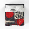 Full view of 60" x 80" Afrocentric geometric art throw blanket featuring bold black, red, gold, cream, and neutral abstract patterns with circles, spirals, grids, and textured African-inspired geometric shapes, laying over a queen size bed with white bed linen.