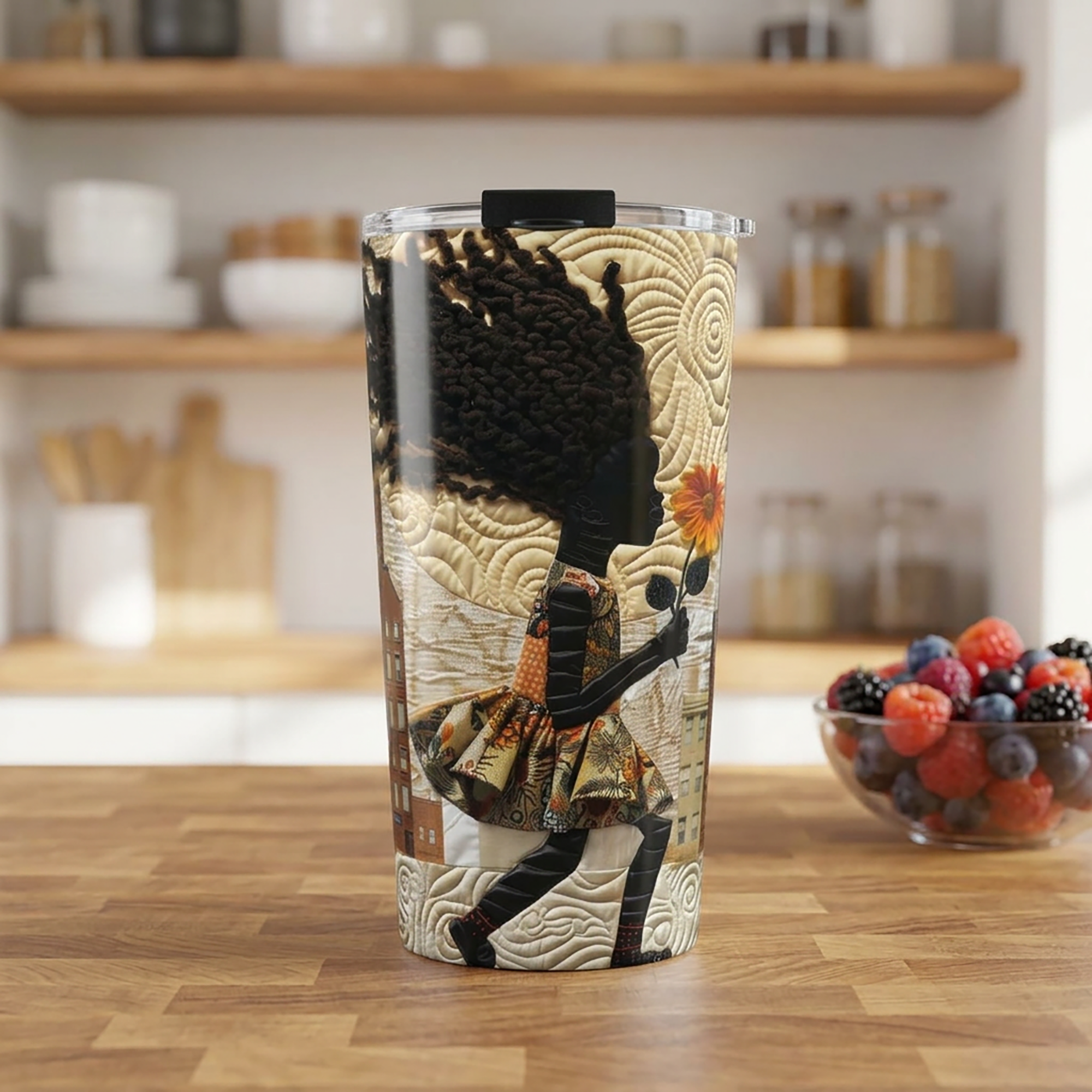 20 oz stainless steel travel tumbler featuring a young Black girl carrying a yellow sunflower while walking through Harlem. Her long braids blow in the wind with historic Harlem brownstones and New York City architecture in the background, illustrated in a colorful Afrocentric faux quilt collage style.  Tumbler is featured on a warm oak wood block table in a kitchen setting.