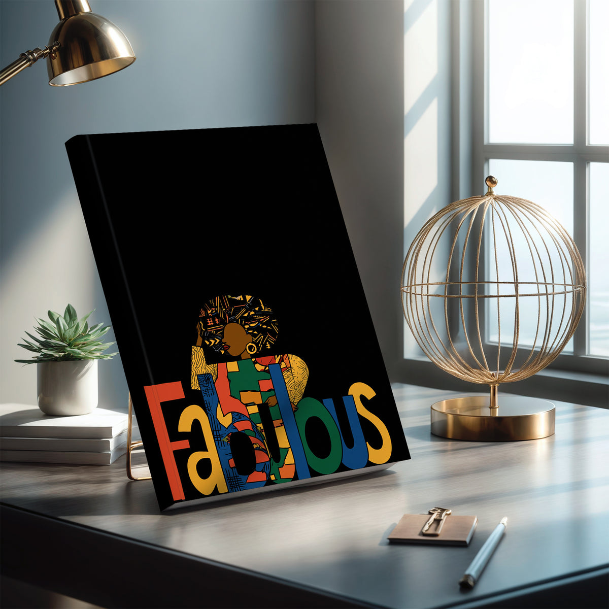 A black hardcover notebook or journal, the front cover features a colorful graphic with the word 'Fabulous' in large multicolored letters and a stylized Afrocentric Black woman above it.