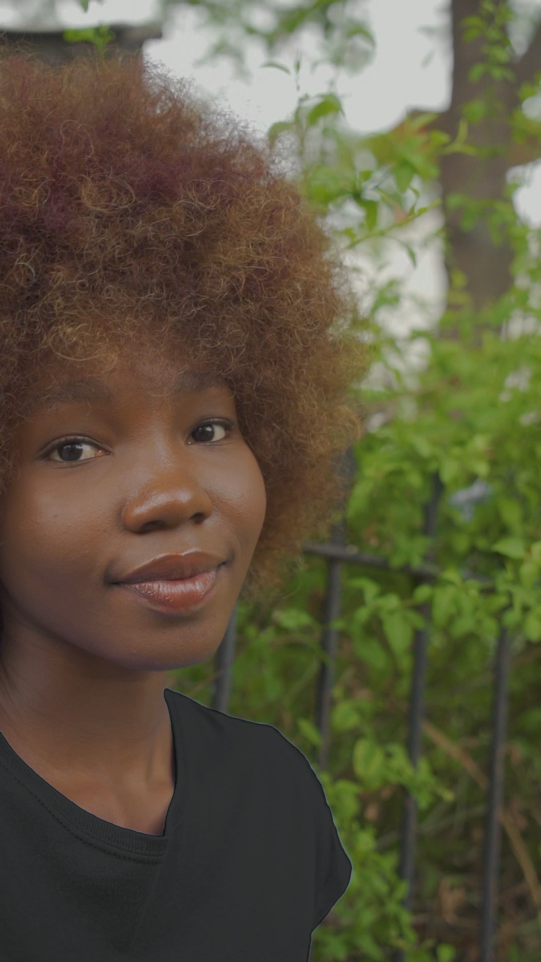 Video of Black young lady wearing the Boss Babe-Kendra tee shirt in black walking through a garden.