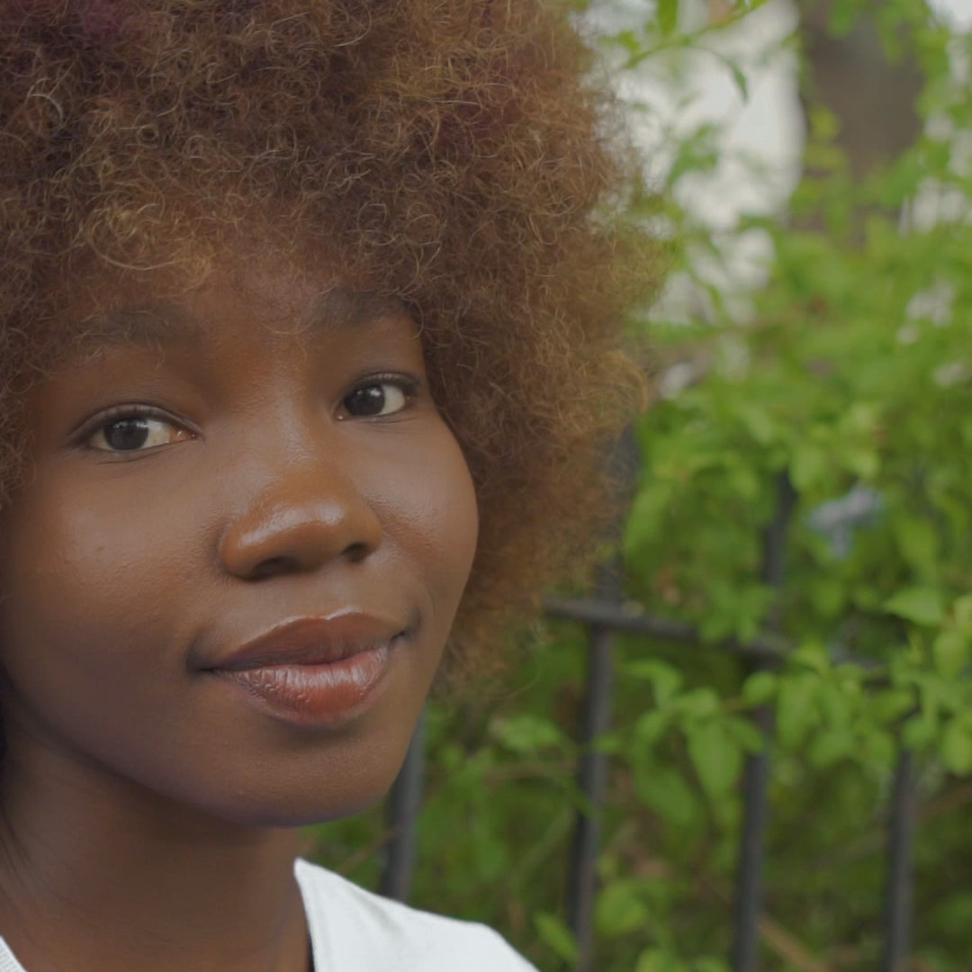 A video featuring a black young woman wearing a white tee shirt with the word "Justice" walking in the woods.  