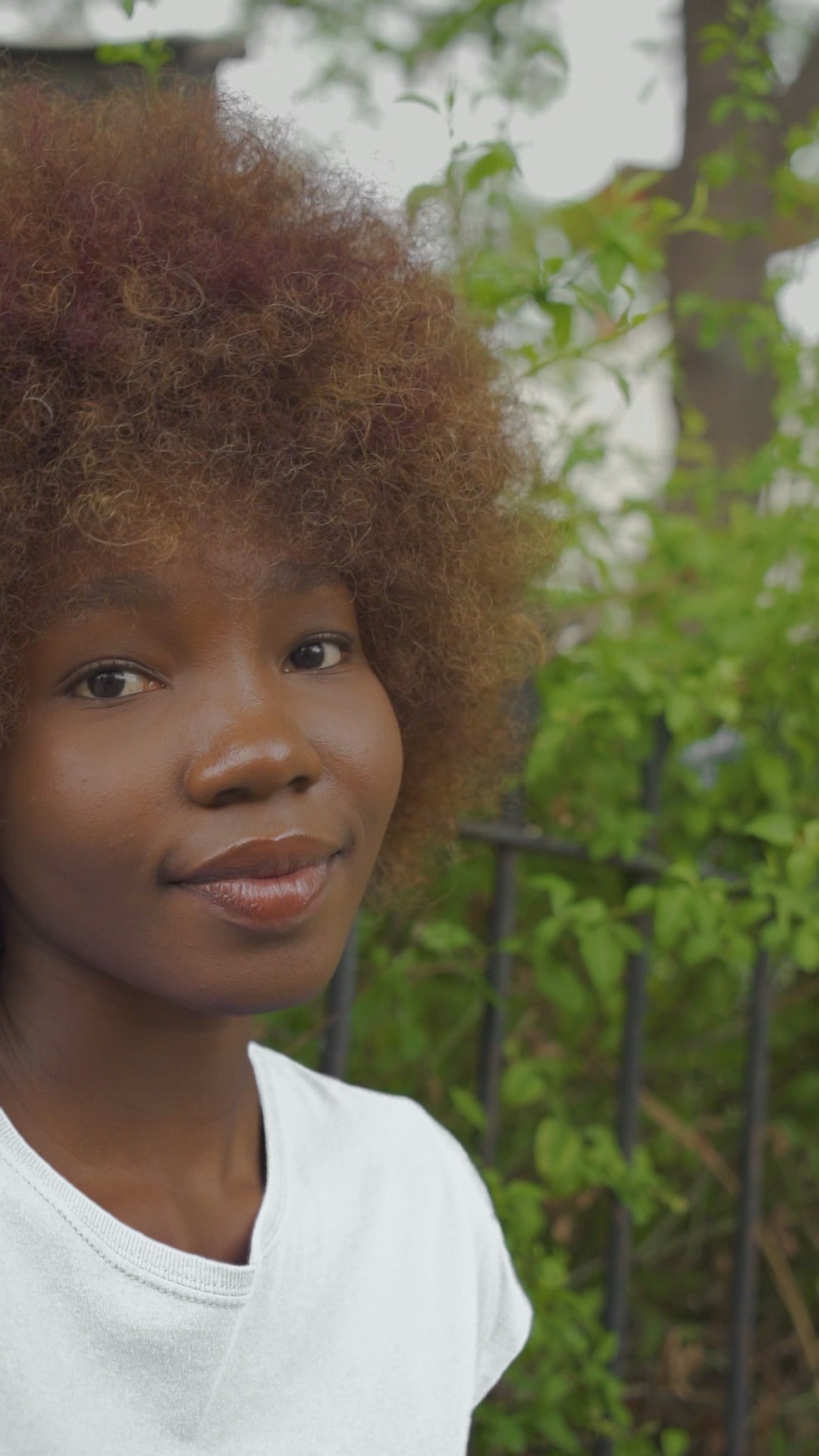 A video featuring a black young woman wearing a white tee shirt with the word "Justice" walking in the woods.  