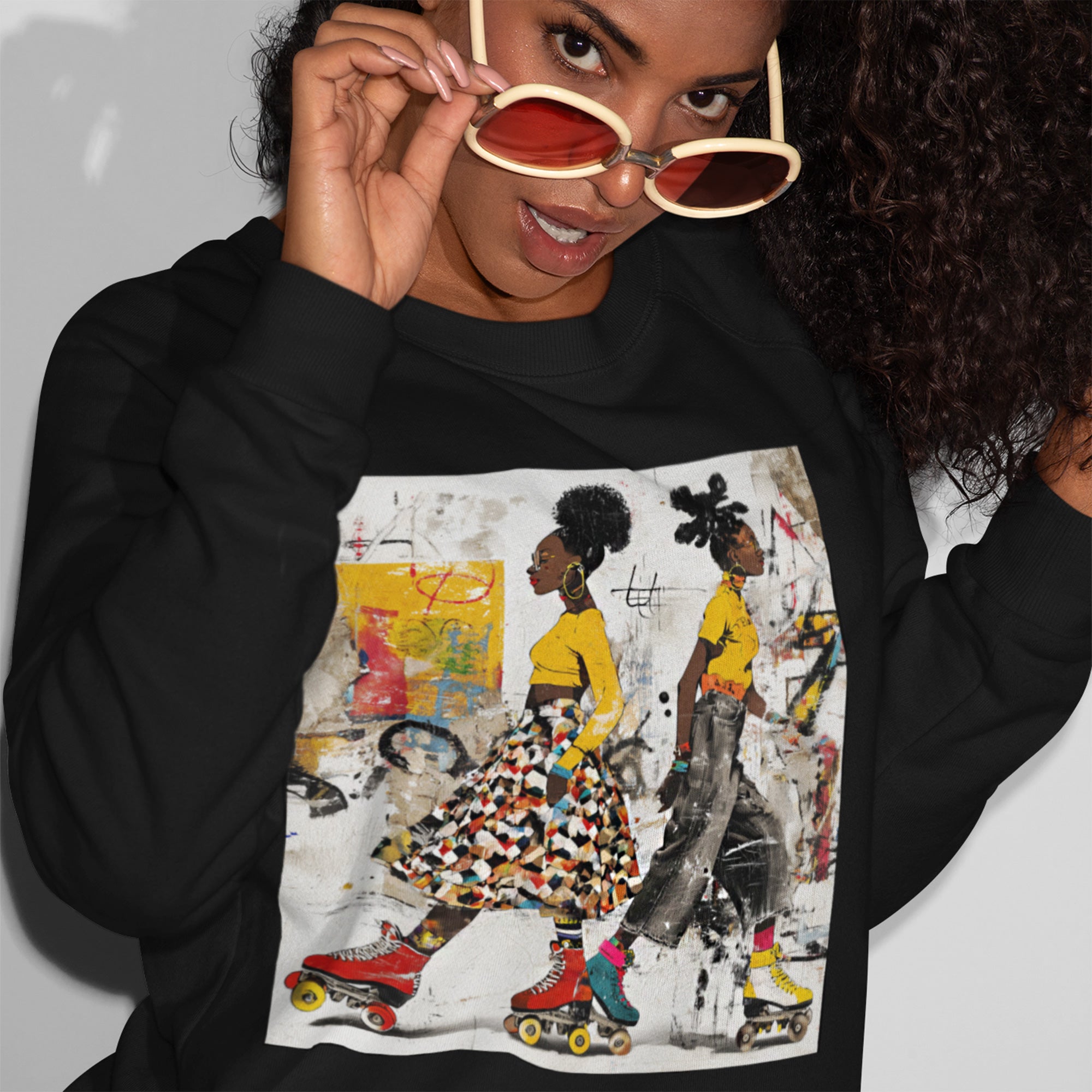 Two Black women with natural hairstyles wearing bold streetwear and roller skates, standing against a colorful abstract graffiti background on an Afrocentric graphic sweatshirt.
