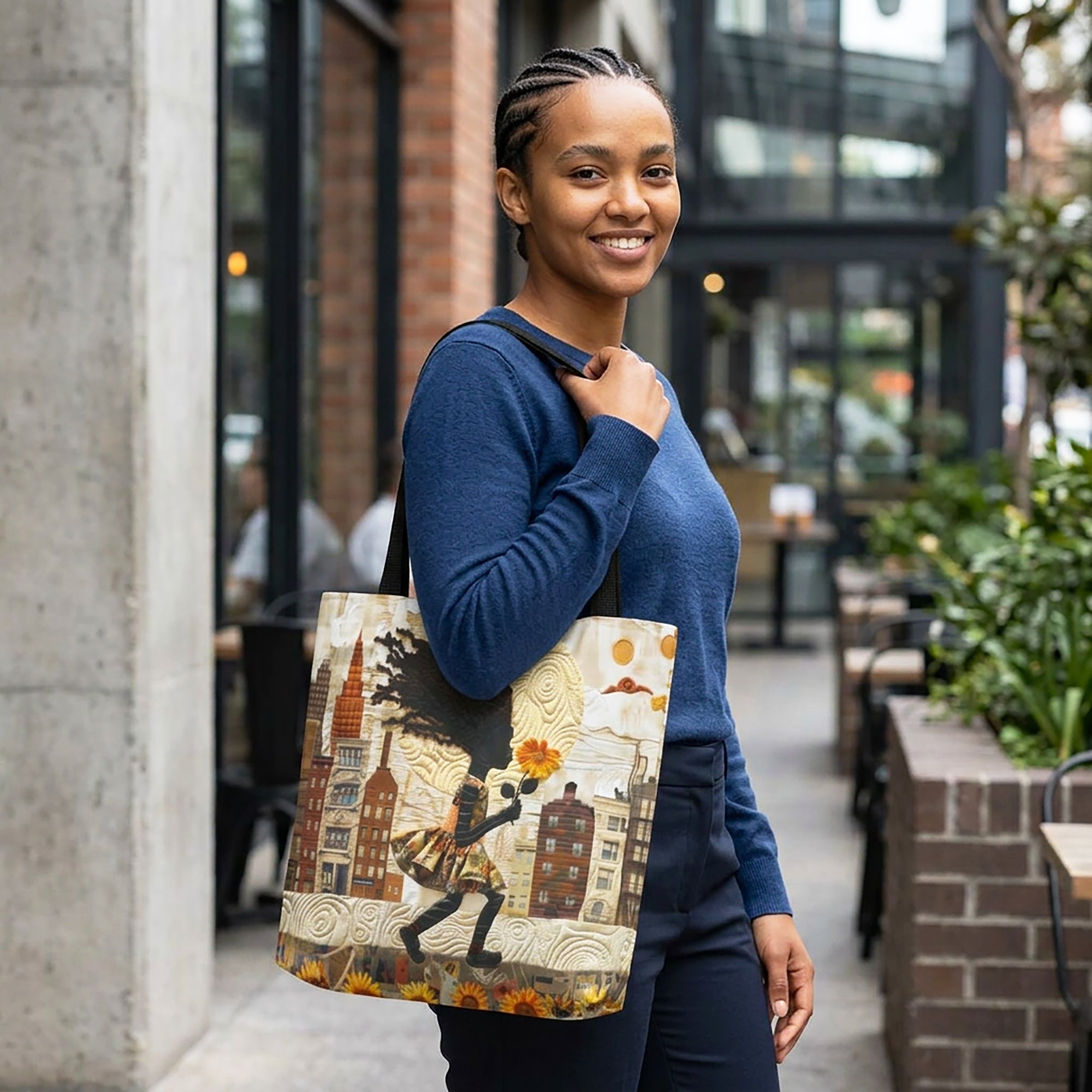 Black young lady carrying a tote bag featuring a young Black girl carrying a bright yellow sunflower while walking through Harlem with long braids blowing in the wind. Historic Harlem brownstones and New York City architecture appear in the background on an Afrocentric faux quilt collage tote bag with a textured 3D-inspired design.
