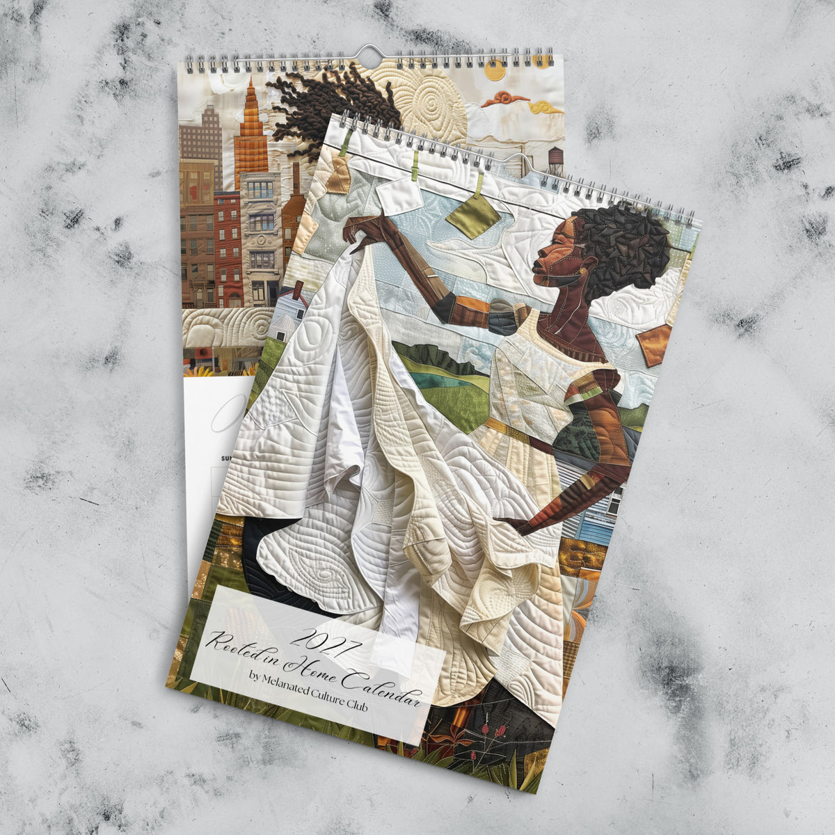Views of front cover and the month of January of an 11" x 17" 2027 Rooted in Home Wall Calendar featuring vibrant African American quilt collage artwork celebrating the everyday lives of Black women, displayed against a grey marble background.