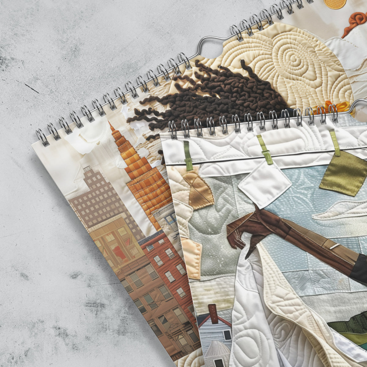 Close up detail of silver hanging wire and grommets of an 11" x 17" 2027 Rooted in Home Wall Calendar featuring vibrant African American quilt collage artwork celebrating the everyday lives of Black women, displayed against a grey marble background.