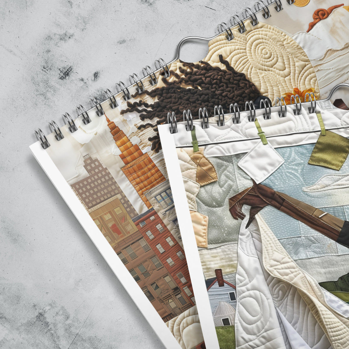Close up detail of silver hanging wire and grommets of an 8" x 11" 2027 Rooted in Home Wall Calendar featuring vibrant African American quilt collage artwork celebrating the everyday lives of Black women, displayed against a grey marble background.